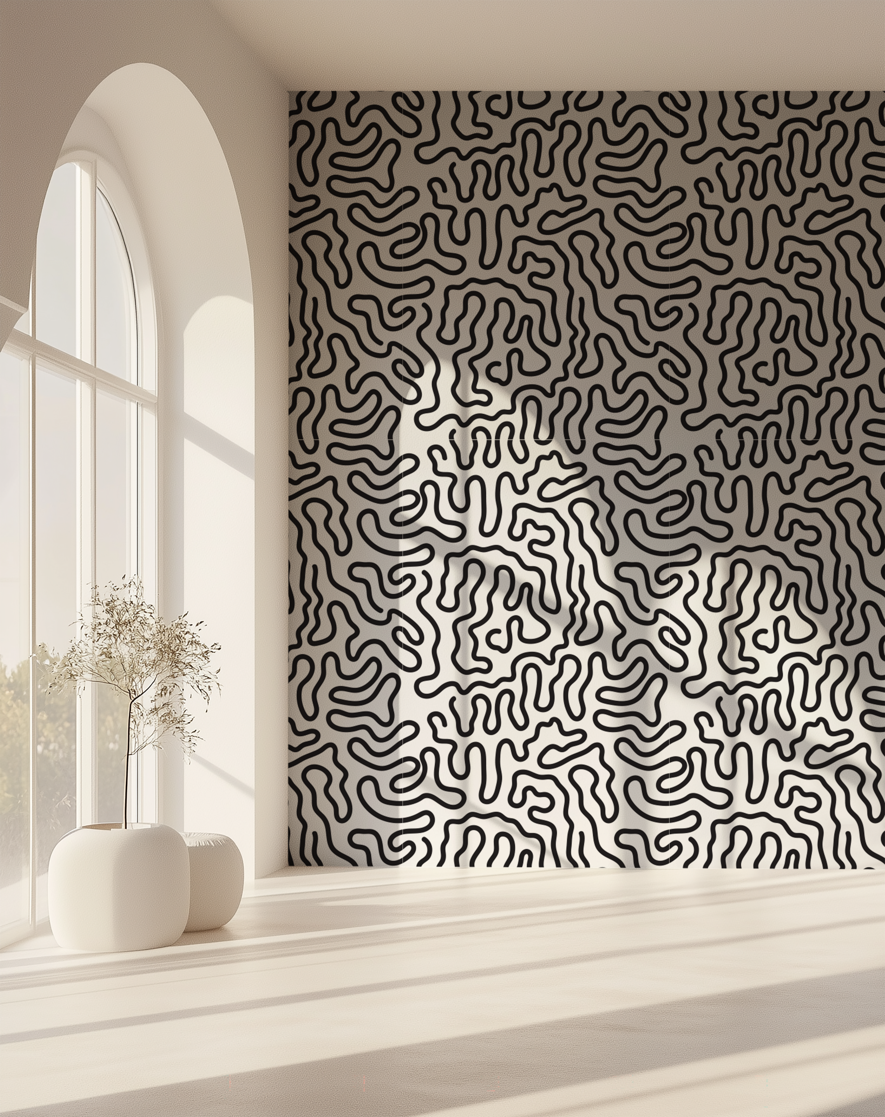 A room interior with a wall covered in a repeating geometric wallpaper of interlocking leaf or petal shapes in turquoise blue on a warm off-white background. Sunlight streams in from an arched window on the left, casting shadows across the wall and floor.