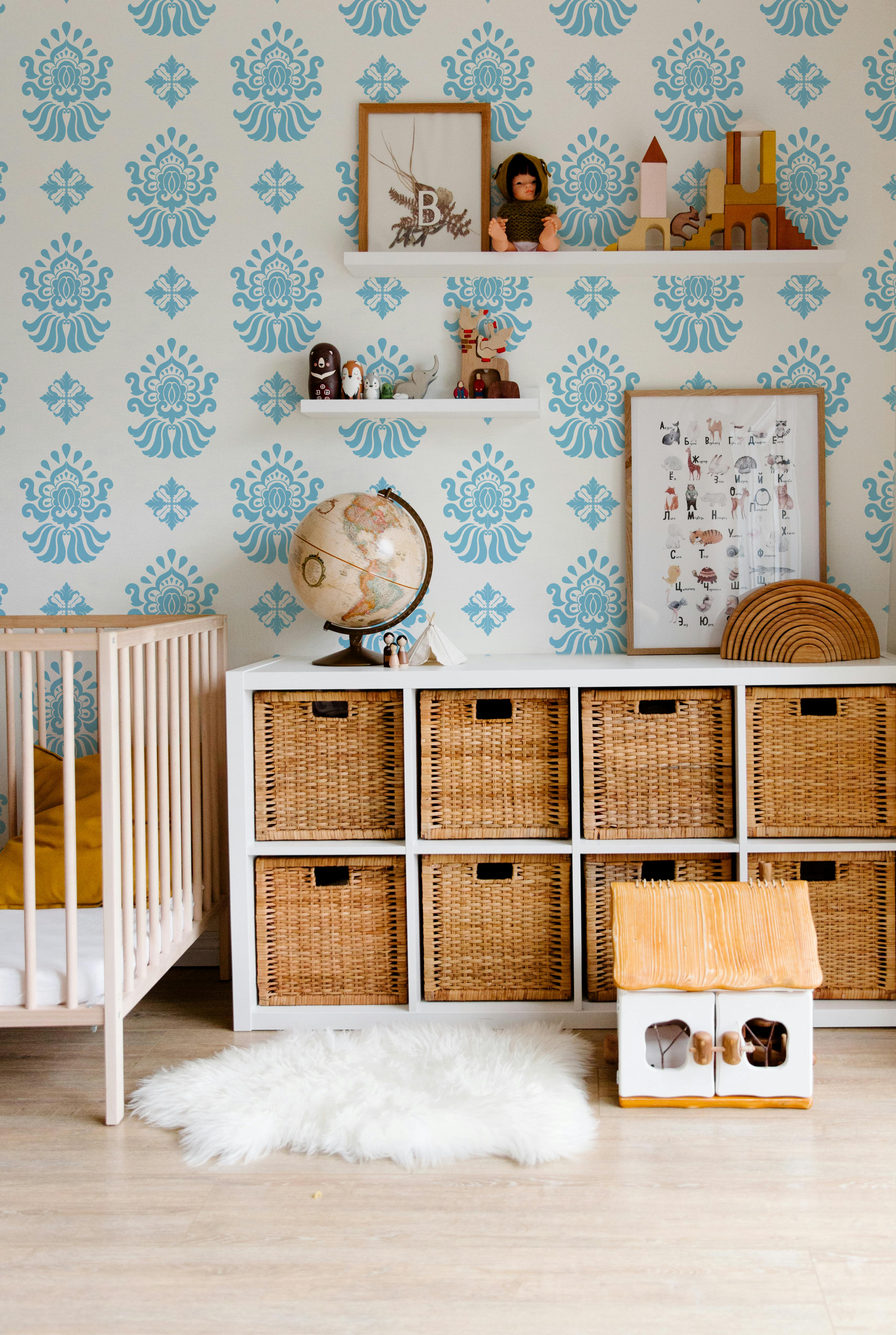 Light blue and cream ornamental wallpaper styled in a nursery and kids room