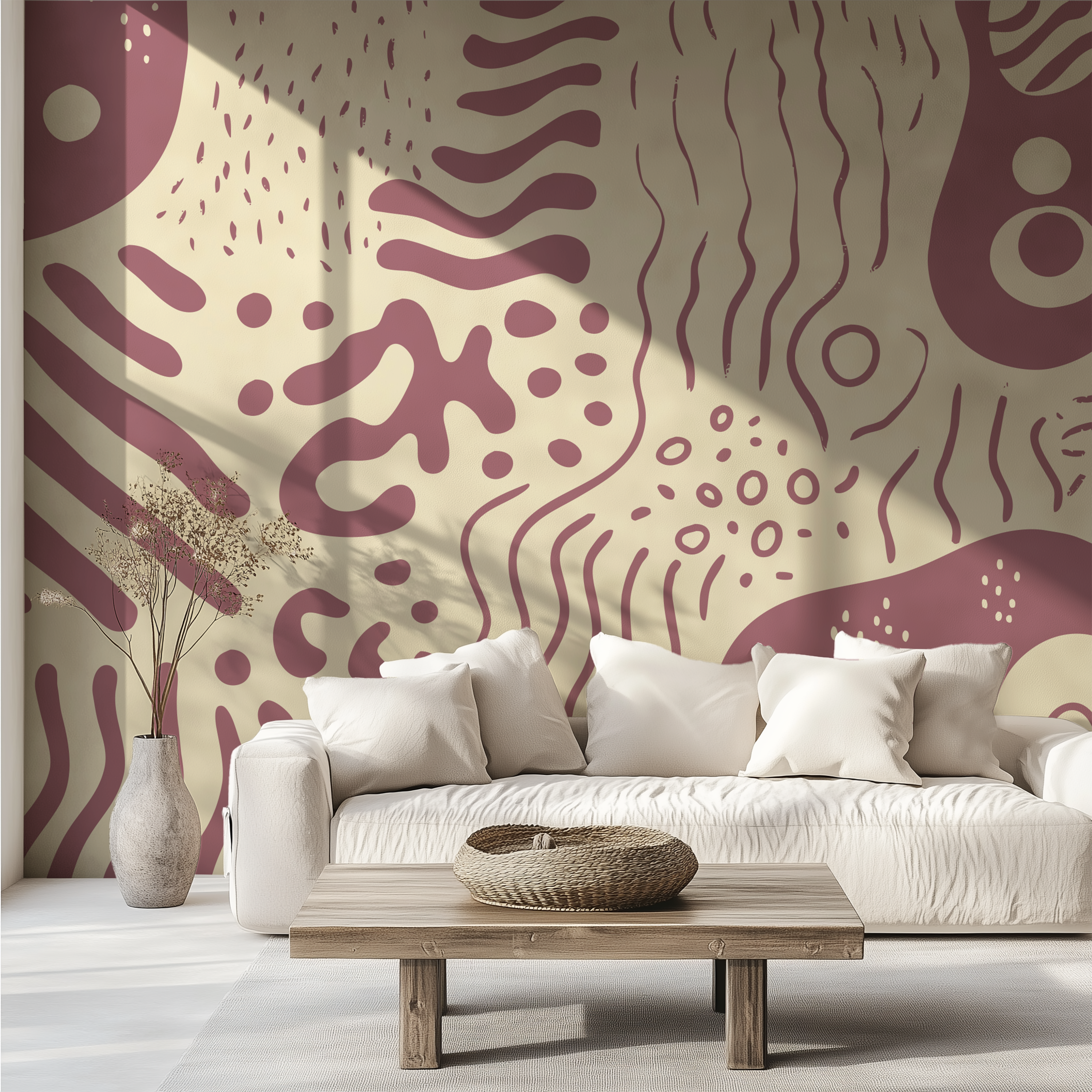 An abstract wallpaper with organic maroon and cream patterns shown in a styled living room setting behind a white sofa with decorative pillows, a wooden coffee table, and a vase.
