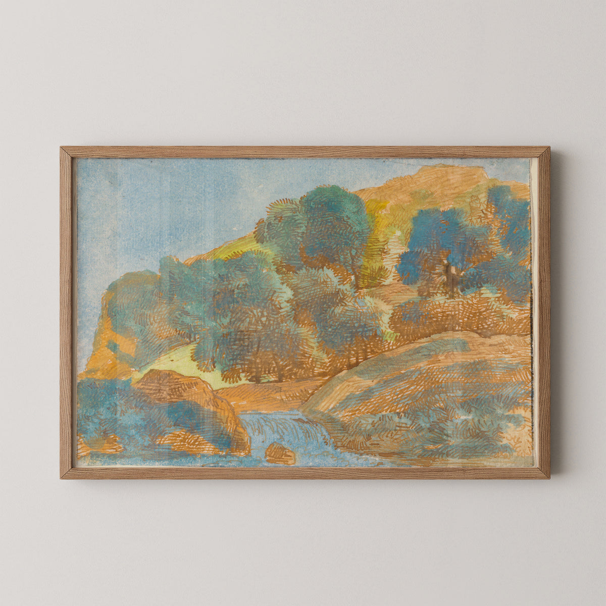 Natural wood-framed Kobell print with winding blue water between rounded green and ochre hills