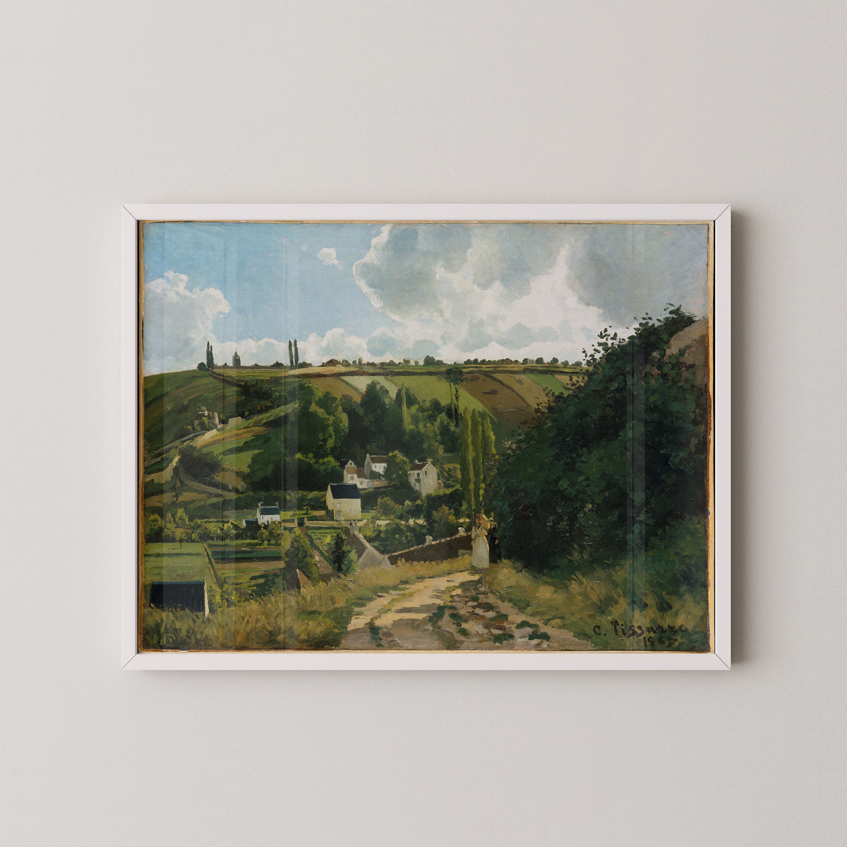 White-framed French countryside art by Pissarro, showing green hills, poplar trees and pale village buildings