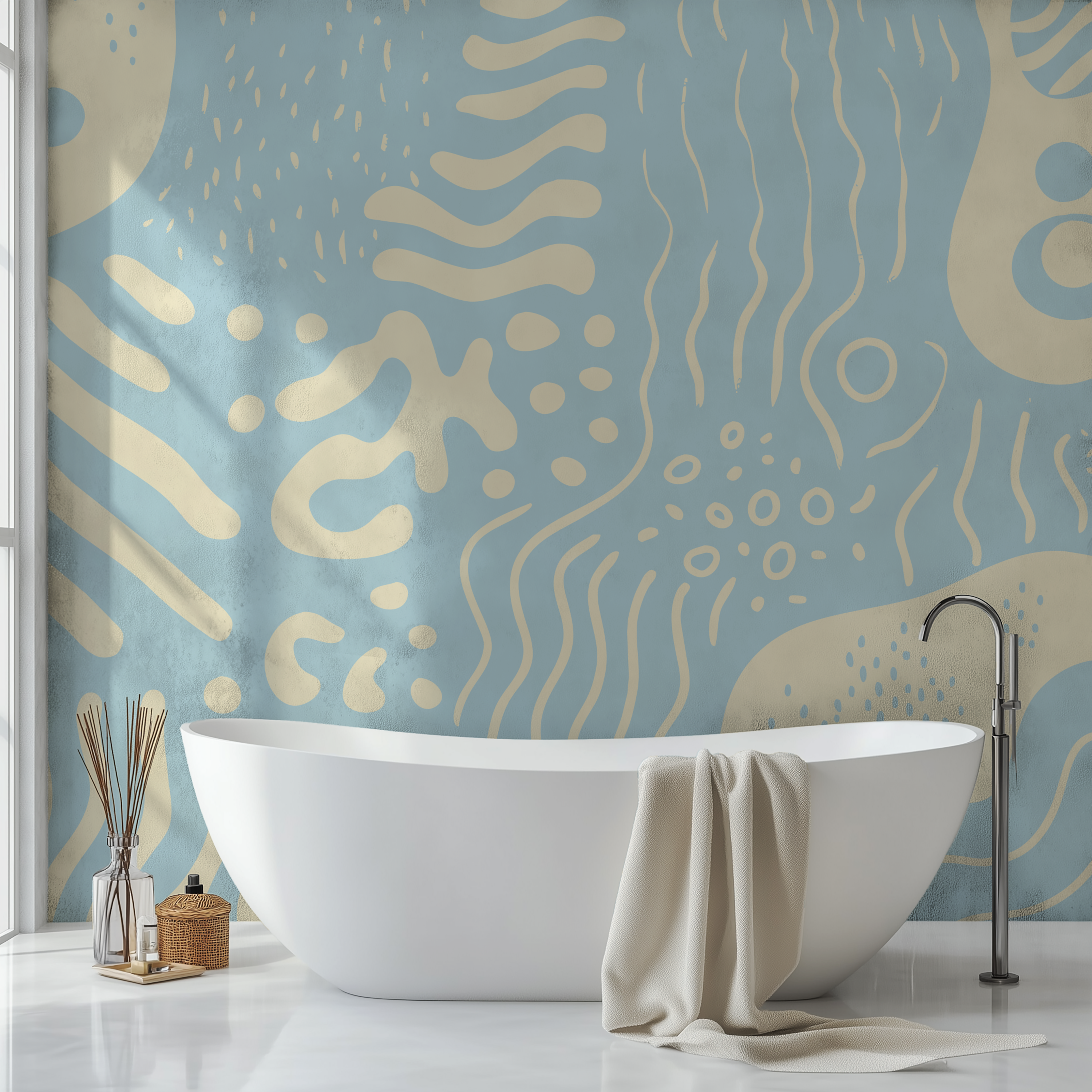 A modern freestanding bathtub in a bright bathroom with a light blue and cream abstract patterned wall, a draped cream towel, and a chrome faucet.