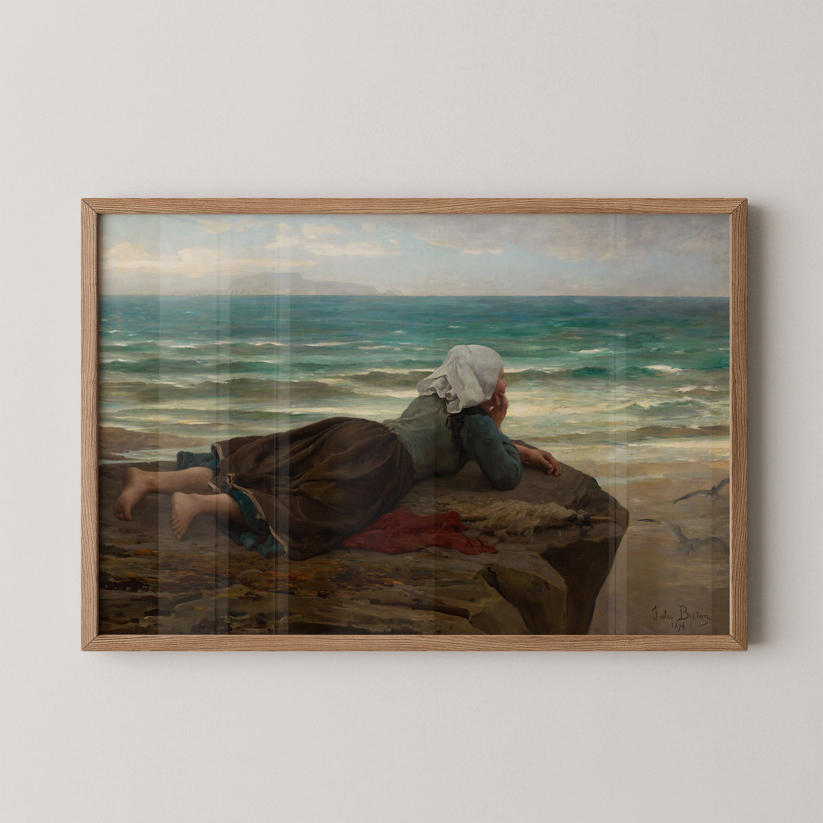 Natural wood-framed Jules Breton print with a reclining figure on brown rocks beside the shoreline