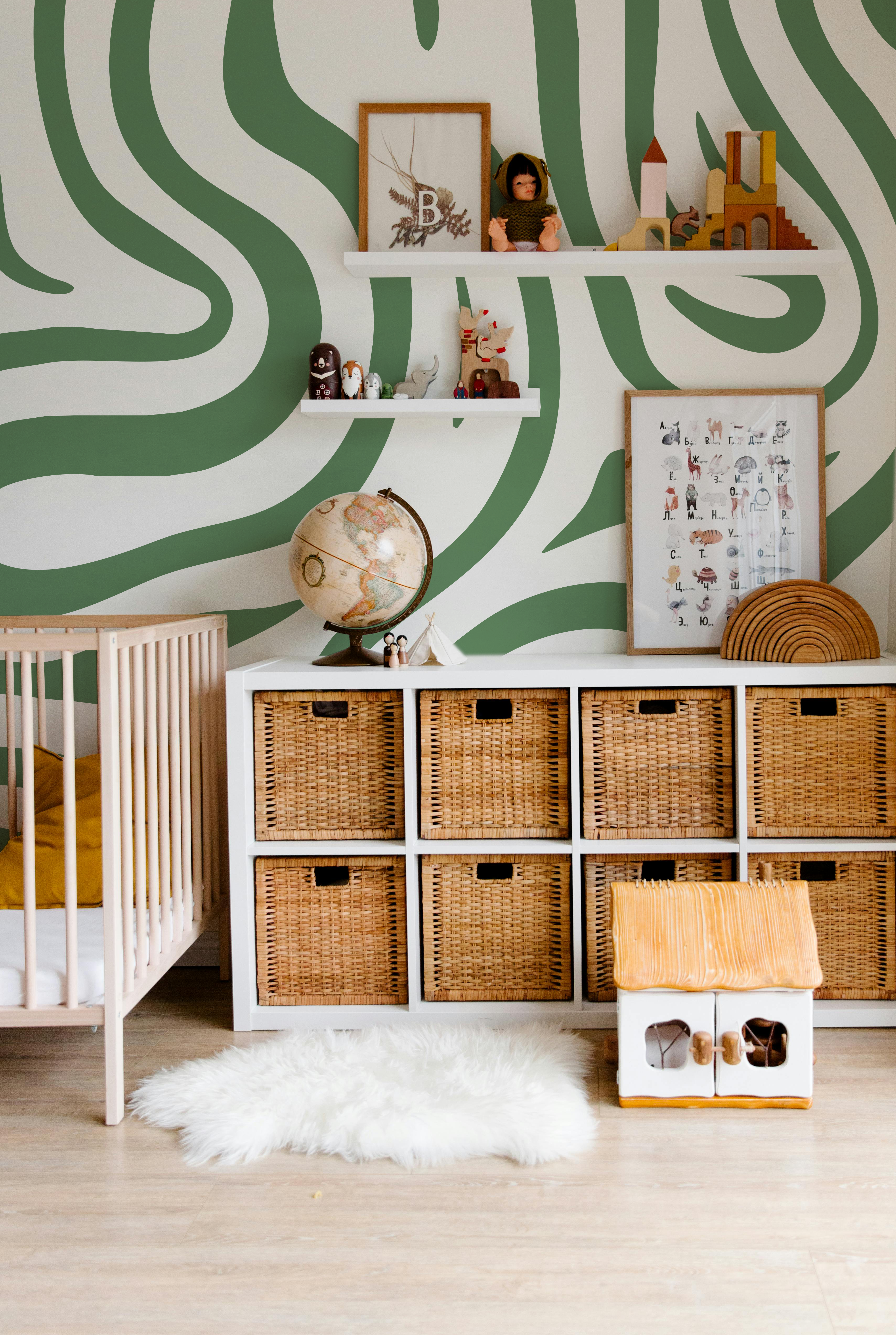 Modern nursery featuring Topo Sage wallpaper with flowing sage green contour lines and natural wood furniture.