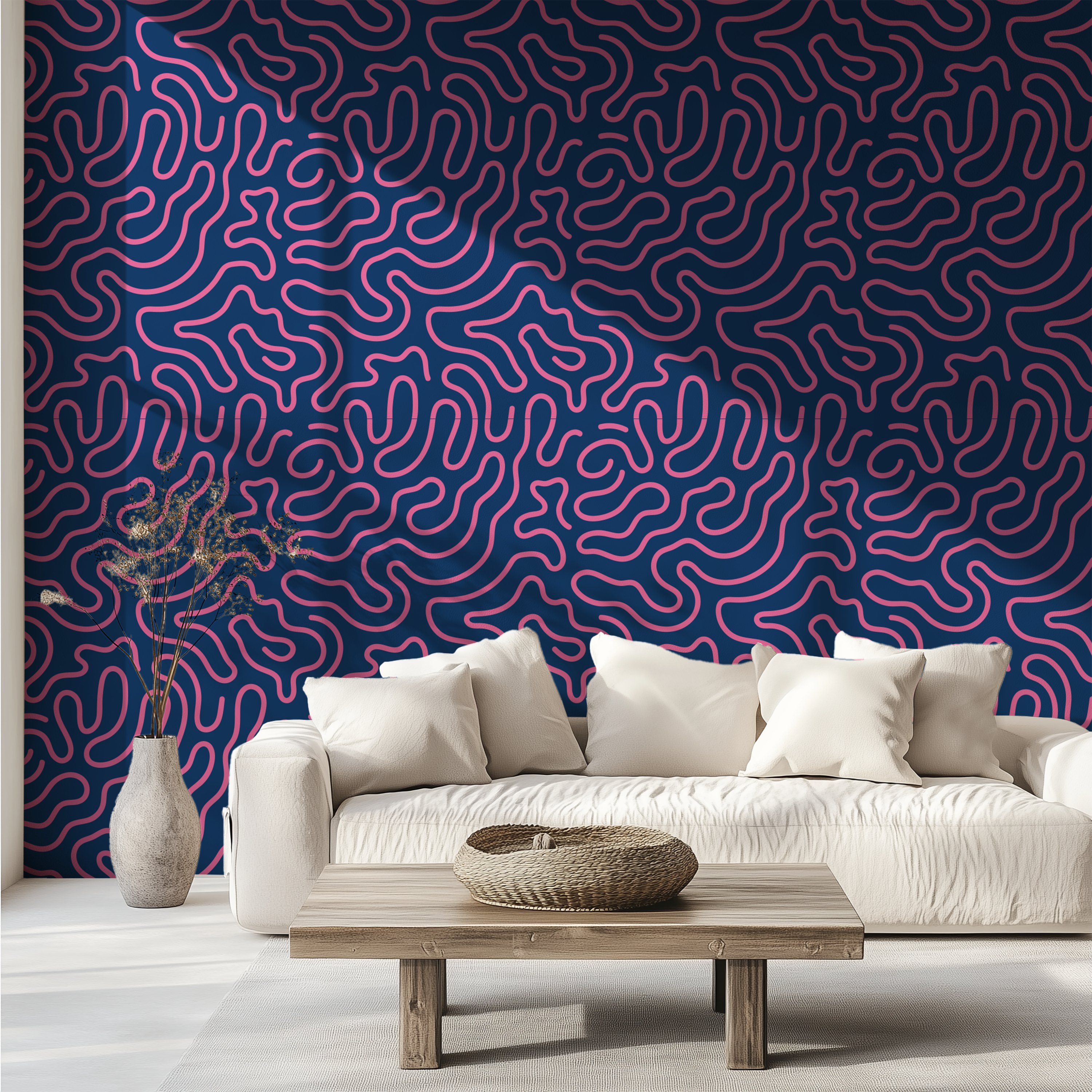 A modern living room setup featuring a bold abstract wavy line wallpaper in navy blue and pink on the back wall, styled with a white textured sofa, a low wooden coffee table, and a decorative vase.